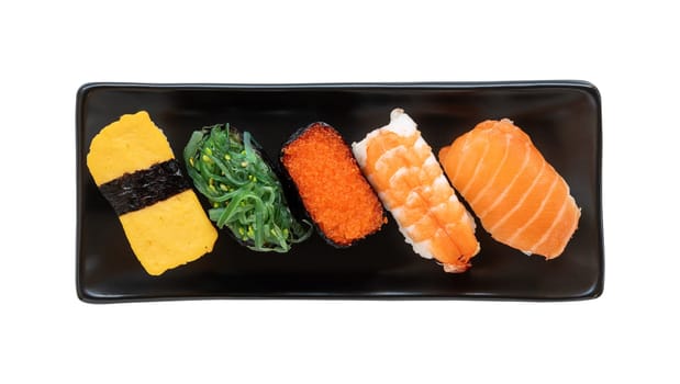 japanese sushi food on black plate. Maki and nigiri with salmon, shrimp, tobiko, seaweed and tomago. Top view of assorted sushi isolated on white background.