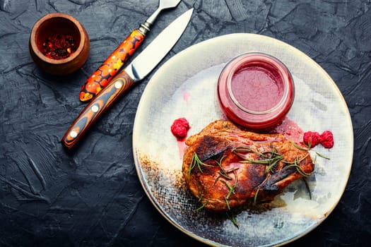 Roasted pork steak on a plate and raspberry sauce