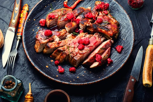 Roasted pork steak on a plate and raspberry sauce