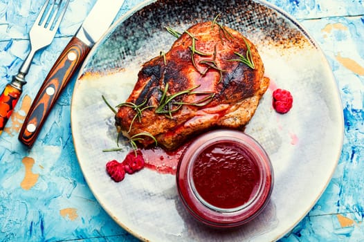 Roasted pork steak on a plate and raspberry sauce