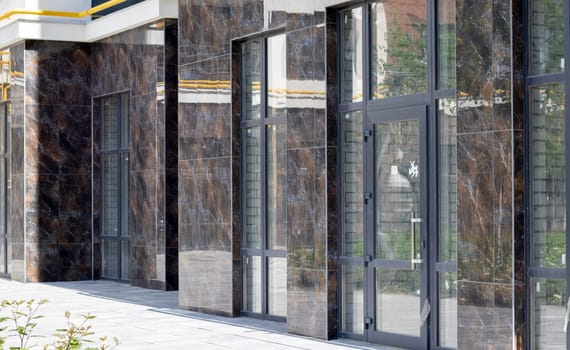 Facade of commercial premises with panoramic windows at street level in a new modern residential complex. Commercial real estate for rent in a typical building