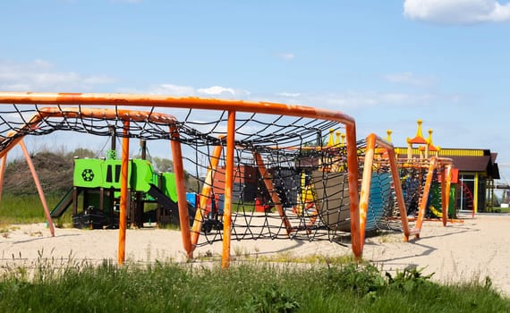 Modern public playground against the blue sky. A colorful play and sports complex for children without people. Equipment for rock climbing and assault on the playground