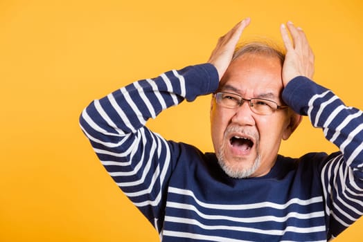 Asian elder man hands holding head and close ears suffering from headache studio shot isolated on yellow background, Portrait senior old man sad suffering from migraine, depressed health care