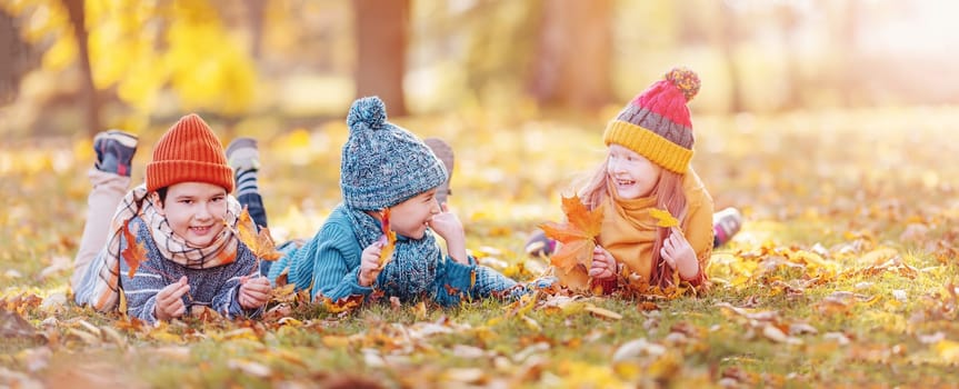 Group of children lying onthe ground in autumnal park. Concept of friendship and family vacation.