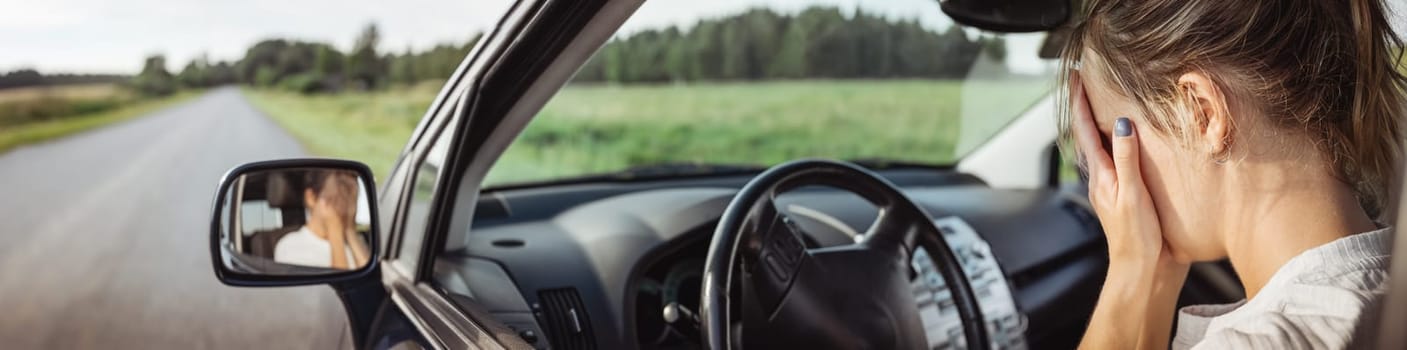 Upset woman sitting in the car and covering face with her hands. Concept of a accident and traffic violations.