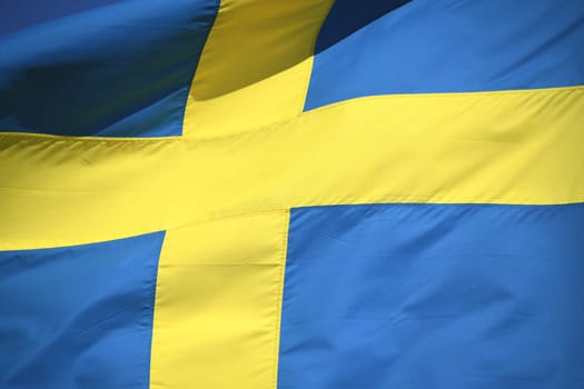 The national flag of Sweden in the colors blue and yellow is waving in the wind. The krone is the currency of Sweden.