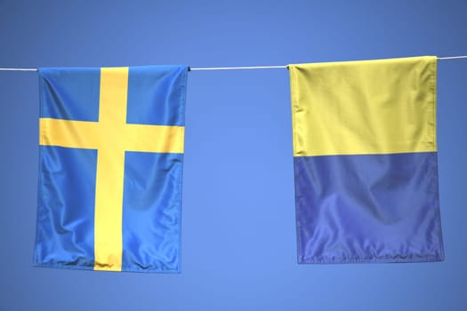 Two blue,yellow Swedish flags,pennants,banners or flags hanging on a string. The blue sky can be seen in the background. Ukraine.