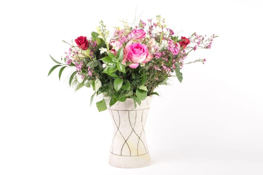 A beautiful flower arrangement in a vase set on a white islolated background.