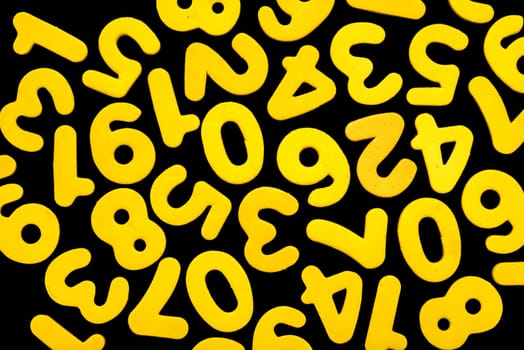 Yellow numbers, from one to nine, including zero, all single ditigits, lie mixed, in no spesific order on a black backgound.