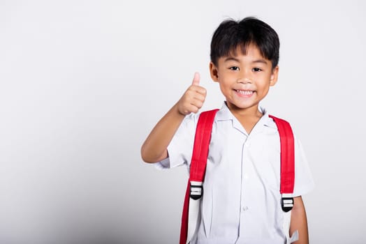 Asian adorable toddler smiling happy wearing student thai uniform red pants show thumb up finger in studio shot isolated on white background, Portrait little children boy preschool, Kid Back to school