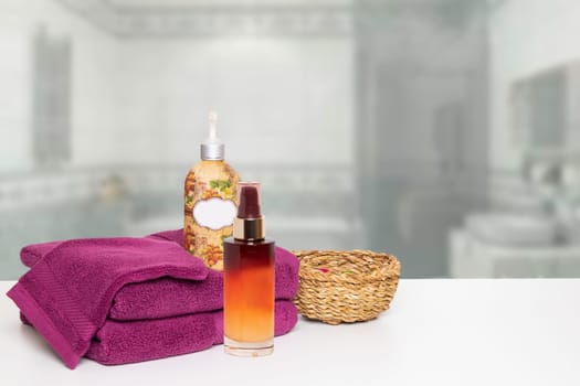 A beautiful composition of spa treatment on the table with towels, massage oil, cream and a basket over blurred bathroom. Space for product display montage.