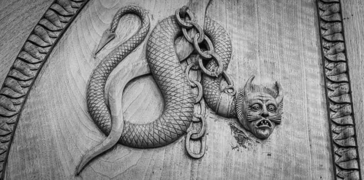 Devil snake symbol. Fantasy magic creature on an old door, 12th Century Abbey, Italy.