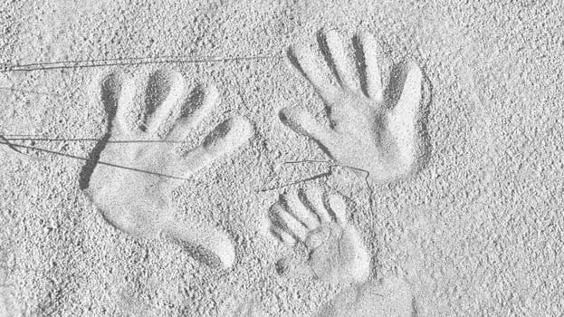 handprints in the sand on the beach of the Baltic Sea in black and white. Connectedness of a family with father, mother and child. Symbol of togetherness for eternity