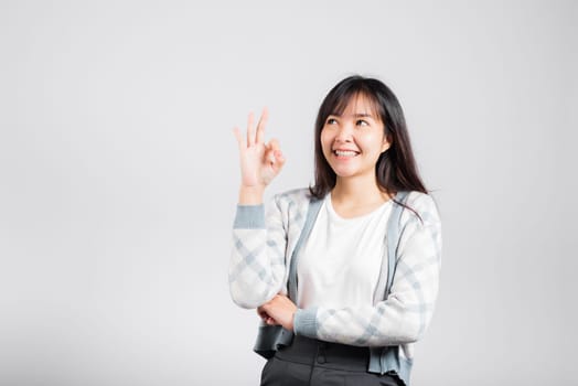 Woman smiling showing made finger OK symbol sign to agree studio shot isolated white background, Happy Asian portrait beautiful young female lifestyle agree hand sign with copy space