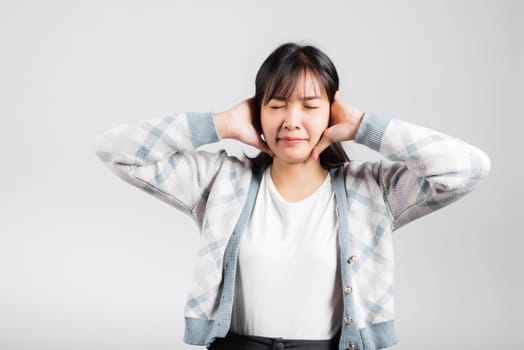 Woman bad mood pain her closed ears with hand palms and close eyes, Asian beautiful young female covers ears for loud noise, studio shot isolated on white background with copy space