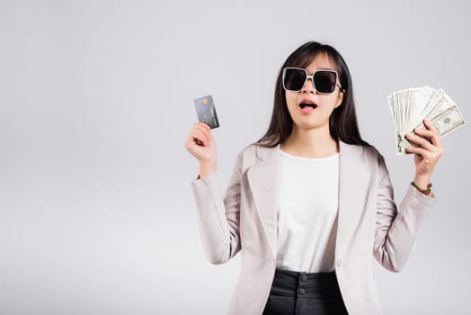 Woman with glasses confident smiling holding dollars money banknote and credit card for payment on hand, Portrait excited happy Asian young female show choose studio shot isolated on white background