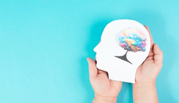 Holding a head with a colorful tree in the hands, symbol for creativity, connection to nature and positive emotion, living in a dream world