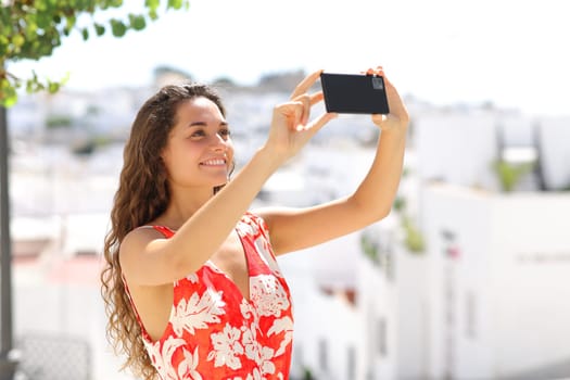 Tourist taking photo with smart phone in a spanish white town