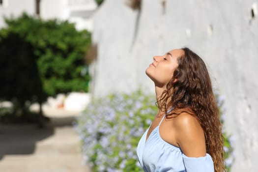 Side view portrait of a woman breathing fresh air in a white town street