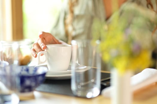 Close up of a woman hand holding a coffee mug in a restaurant