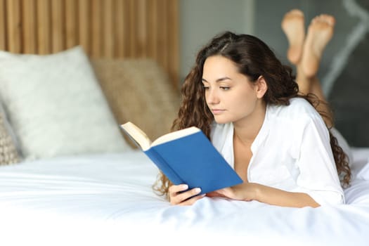 Woman reading a book relaxing on the bed in the bedroom