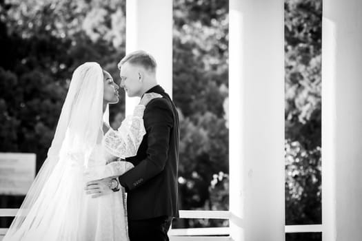 Mixed-racial newlyweds on a walk hugging and looking lovingly at each other, black and white photography