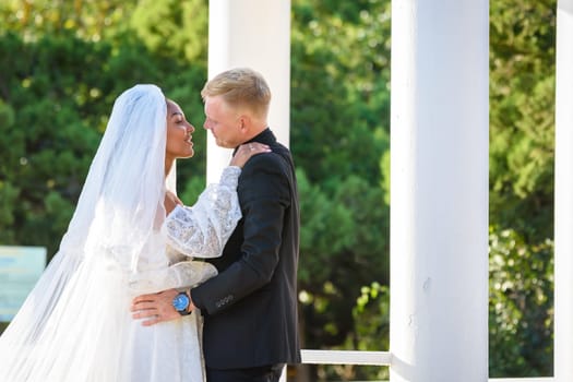 Mixed-racial newlyweds on a walk hugging and lovingly look at each other