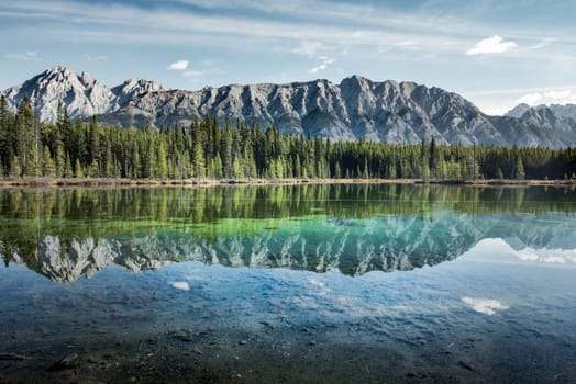 Sky and peaks are reflected in a crystal clear mountain lake