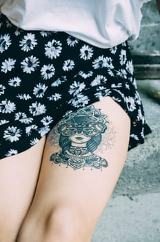 Street style hipster woman with artistic body tattoo on her leg closeup. Outdoor youth and lifestyle concept.