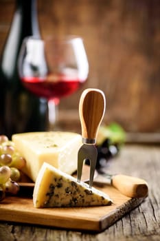 Wine and dine restaurant. Glass of red wine and blue cheese with grapes on rustic wooden table.