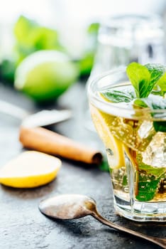 Mojito cocktail making at bar. Cocktail ingredients for summer party refreshment drink preparation. Lime, mint, sugar, vodka and gin on dark rustic background.
