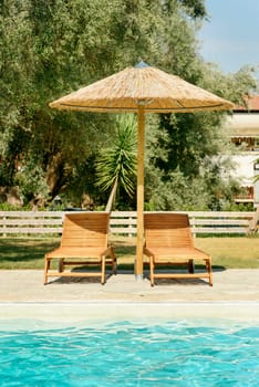 Sun beds and parasol at swimming pool in greece