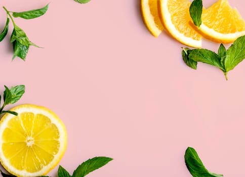 Citrus slices and mint herbs frame on retro pastel pink background with copyspace
