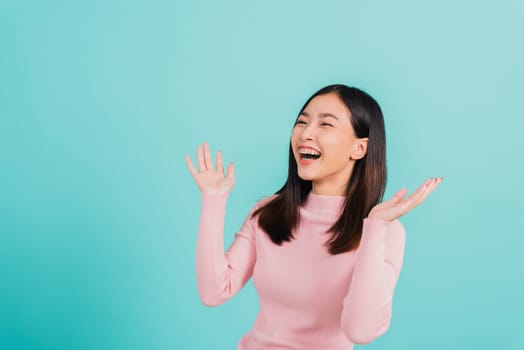 Happy young Asian beautiful woman smiling wear silicone orthodontic retainers on teeth surprised she is excited screaming and raise hand make gestures wow, studio shot isolated on blue background