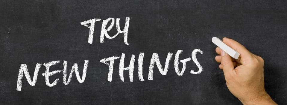 Text written on a blackboard - Try new things
