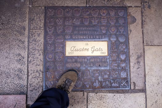 Barcelona, Spain - Dec 29th, 2019: Els Quatre Gats cafe. Winter visitor walking over ground plaque