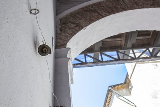 Mechanically operated doorbell on a torsion spring actuated by a wire. Bell nailed to whitewashed wall