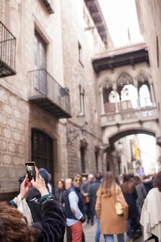 Tourist taking pictures to Bridge at Bisbe street, Barri Gotic, Barcelona. Spain