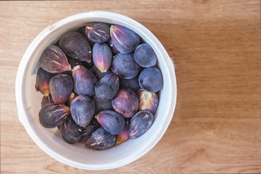Bucket full of fresh fig just harvested. Studio shot with natural light. Wooden background