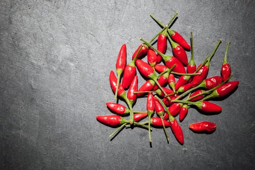 Black slate with piri-piri chili pepper. Studio shot with natural light. Wooden background