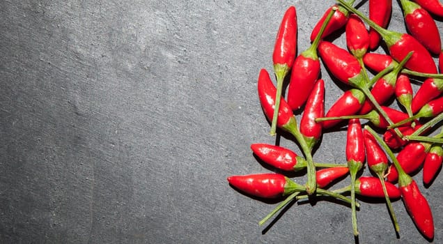 Black slate with piri-piri chili pepper. Studio shot with natural light. Wooden background