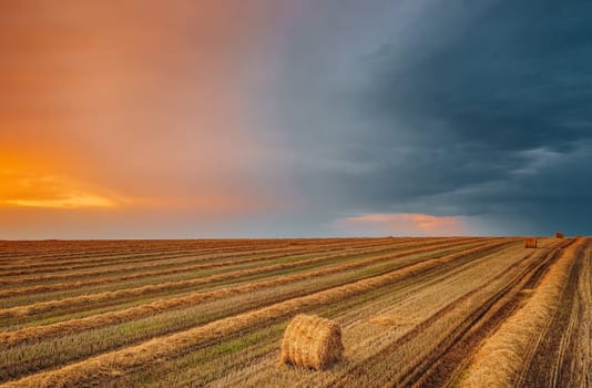 Aerial View Of Sunset Bright Sky Above Summer Hay Field Landscape In Evening. Haystack, Hay Roll in Sunrise time.