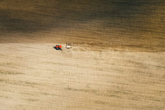 Aerial View. Tractor With Seed Drill Machine Sowing The Seeds For Crops In Spring Season. Beginning Of Agricultural Spring Season. Countryside Field Landscape. Natural Rural Background.