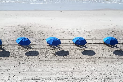 Beach umbrellas in a row on sandy beach