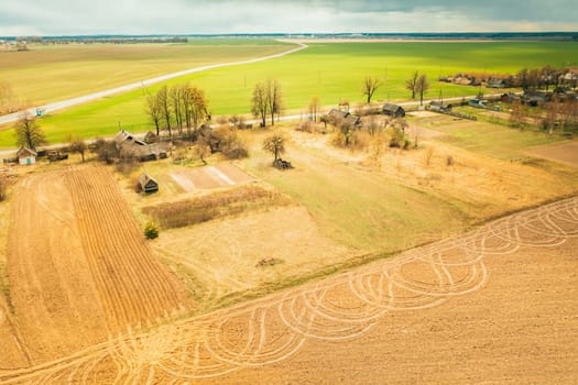 Belarus. Aerial View Of Belarusian Village. Beautiful Rural Landscape In Bird's-eye View. Beginning Of Agricultural Spring Season. Tracks On Plowed Field From Agricultural Machinery.