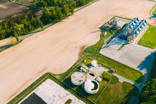 Biogas Bio-gas Plant From Pig Farm And Granary, Grain-drying Complex, Commercial Grain Or Seed Silos In Sunny Spring Rural Landscape. Corn Dryer Silos, Inland Grain Terminal, Elevators.