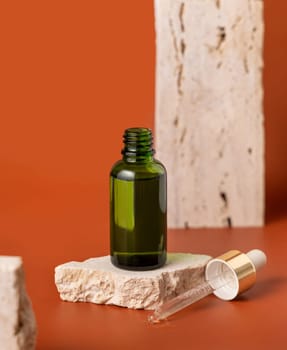 Opened Green dropper bottle on beige stone on red close up, cosmetic Mockup. Skincare beauty product, serum or essential oil. Natural cosmetics..