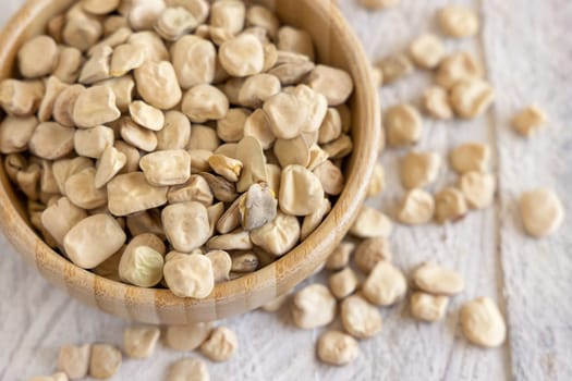 Bowl of raw dry Grass pea close up on wood. Healthy, protein source for vegan and vegetarian diet. Traditional Italian apulian cuisine ingredient. Legumes known as Cicerchia, Vetch, Blue Sweet Pea