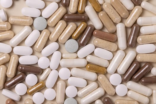 Mix of medical capsules and pills on light beige top view. Preventive medicine and healthcare, taking dietary supplements and vitamins. Assorted pharmaceutical medicine capsules