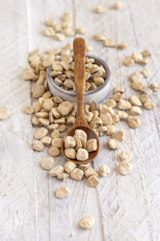 Spoon of raw dry Grass pea close up on wood. Healthy, protein source for vegan and vegetarian diet. Traditional Italian apulian cuisine ingredient. Legumes known as Cicerchia, Vetch, Blue Sweet Pea